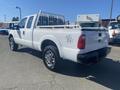 A white 2014 Ford F-250 SD with a flatbed and a metal railing in the truck bed, featuring chrome rims and four-wheel drive designation
