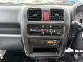 Dashboard of a 2009 Suzuki Carry featuring climate control knobs a digital clock and a radio with a display