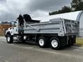 A white 2017 International WorkStar 7600 dump truck with a silver cargo bed raised at the rear and hydraulic lift mechanism visible
