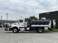 A 2016 Peterbilt 348 truck with a large black water tank mounted in the bed and equipment in a red frame attached to the side