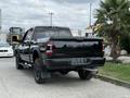 A black 2024 RAM 2500 truck is parked with its rear facing the viewer showcasing the RAM logo on the tailgate and rugged tires