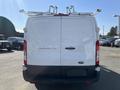 A white 2016 Ford Transit van with a plain rear design and mounted roof racks