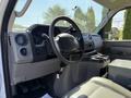 Interior view of a 2011 Ford Econoline showing the steering wheel dashboard and gear shifter with beige seating and console