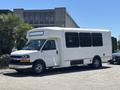 A 2020 Chevrolet Express white shuttle bus with large windows and a low profile parked on a street