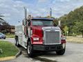 A red and silver 2007 Freightliner FLD120 truck with chrome exhaust stacks and amber lights on top parked with a shiny grille and large wheels