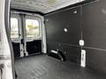 A 2021 Ford Transit van interior with a spacious cargo area featuring a black paneled wall and a rubber floor mat for load protection