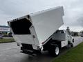 A 2013 Ford F-650 truck with a large white dump bed tilted upwards revealing a spacious cargo area and equipped with lights on the rear