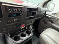 Interior of a 2009 Chevrolet Express featuring the dashboard with a radio and climate controls along with cup holders and part of the driver's seat visible