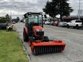 A 2018 Kubota B2650 tractor with a front-mounted broom attachment parked on a street