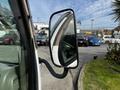 A side mirror of a 2004 Toyota Toyoace reflecting the interior and a glimpse of parked vehicles in the background