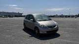 A silver 2006 Honda Fit parked with its front angled slightly towards the viewer showcasing its compact design and distinctive Honda branding