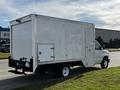 A white 2013 Ford Econoline cargo van with a boxy cargo area and a side door parked on the street