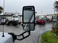 A side mirror of a 2015 Chevrolet Express showing a reflection of vehicles behind it in a rainy setting