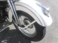 A close-up of the front wheel and fender of a 1947 Harley-Davidson WL featuring a white fender and a spoke wheel with a chrome hub