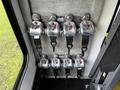 A set of six metal seatbelt latches with red release levers mounted on a gray surface inside a vehicle