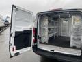 An open 2018 Ford Transit van with a spacious cargo area featuring metal shelving and a partitioned section at the rear