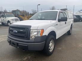 A white 2013 Ford F-150 pickup truck with a black grille and a cap on the bed is positioned in the foreground