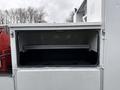 A compartment of a 2000 Ford F-450 truck with an open door revealing a shelf inside
