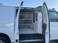 A white 2012 GMC Savana van with its side doors open revealing a spacious interior designed for cargo storage and shelving