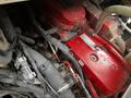 A red engine block with various hoses and electrical connections visible some parts are worn and covered in dirt and oil