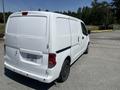 A white 2019 Nissan NV200 van parked with its rear view visible showing a simple design and sliding side door
