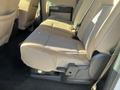 The interior of a 2014 Ford F-350 SD showing a beige rear bench seat with fabric upholstery and a fold-down armrest