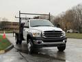 A 2008 Sterling Bullet truck with a flatbed and a metal rack in the back is parked on a wet road