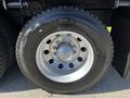 Close-up of a large tire from a 2012 Freightliner M2 112 featuring a silver rim and thick black tread designed for heavy-duty use