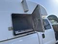 A 2014 Ford F-350 SD with an open side access compartment revealing a metal interior and equipment storage features