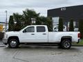 A white 2013 Chevrolet Silverado 3500HD with a double cab and long bed parked on a paved surface