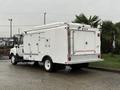 A white 2014 International TerraStar truck with a fitted service body featuring multiple compartments and a rear door with safety markings