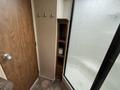 A 2013 Outdoor Wind River featuring a wooden door with hooks and a small shelf with rolled towels and toiletries inside a bathroom space