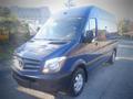 A blue 2017 Mercedes-Benz Sprinter van with a high roof and large windshield positioned slightly to the right with visible headlights and a front grille