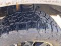 A close-up of a rugged tire from a 2000 Ford F-350 SD showcasing deep tread patterns and a shiny wet surface