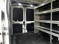 Interior view of a 2020 Ford Transit with shelving units attached to the walls and a spacious cargo area