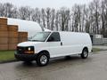 A white 2014 GMC Savana van with a black front grille and silver wheels is parked on a pavement