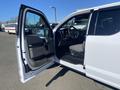 A white 2019 Ford F-150 with the driver's side door open revealing the interior and steering wheel