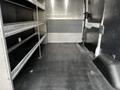 A 2020 Ford Transit interior with metal shelving on one side and a spacious, flat rubber floor suitable for cargo transport