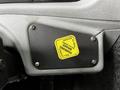 A black metal parking brake lever with a yellow warning label reading "PULL TO RELEASE" mounted on a light gray dashboard surface