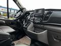 Interior view of a 2020 Ford Transit with a steering wheel center console and gear shift visible