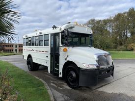 A 2016 International 4200 bus in white with black accents showcasing large windows and a distinctive front design