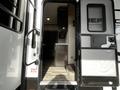 A 2021 Grand Design Recreational 311BHS showing an open entry door revealing an interior with a kitchen area and cabinets visible inside