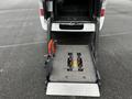 A 2002 Nissan Van with a wheelchair lift extended at the rear featuring a metal platform and safety handles