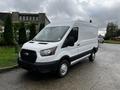 A white 2021 Ford Transit van with a black grille and standard tires parked on a street