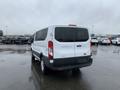 A 2017 Ford Transit van in white with a high roof and sliding side door parked in a wet lot