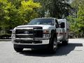 A 2009 Ford F-550 truck with a white and black exterior, featuring a flatbed and chrome grille with integrated lights