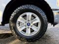 A close-up view of a 2018 Ford F-150 wheel showcasing a silver alloy rim and an off-road tire with deep treads.