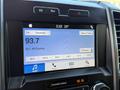 A close-up view of a Ford F-550 dashboard display showing a radio interface with the frequency 93.7 and options for audio settings and presets