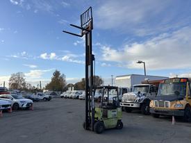 A green 2000 Clark GPS 15 forklift with a tall vertical mast and two forks extending from the front