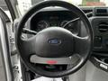 Steering wheel of a 2013 Ford Econoline with a Ford logo and dashboard controls visible in the background